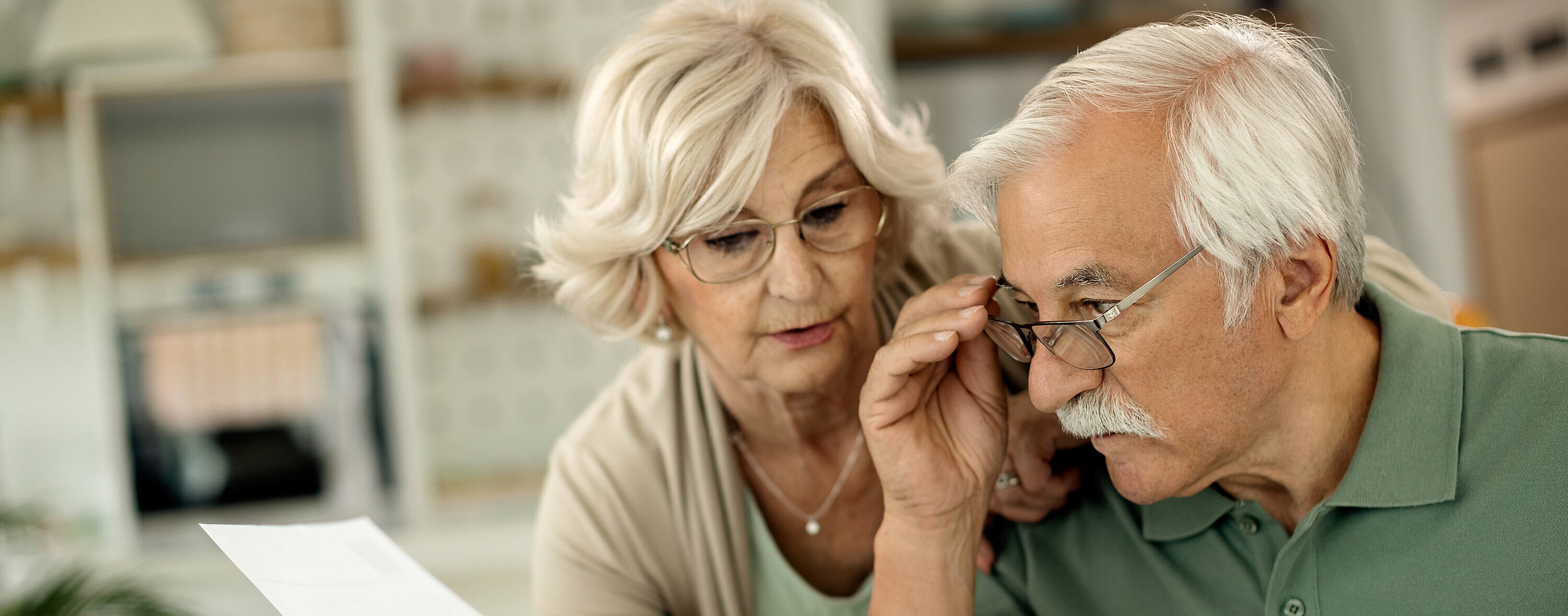 Eine ältere Dame und ein älterer Herr betrachten ein Schriftstück.