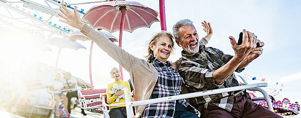 Happy senior couple taking a selfie during amusement park ride.