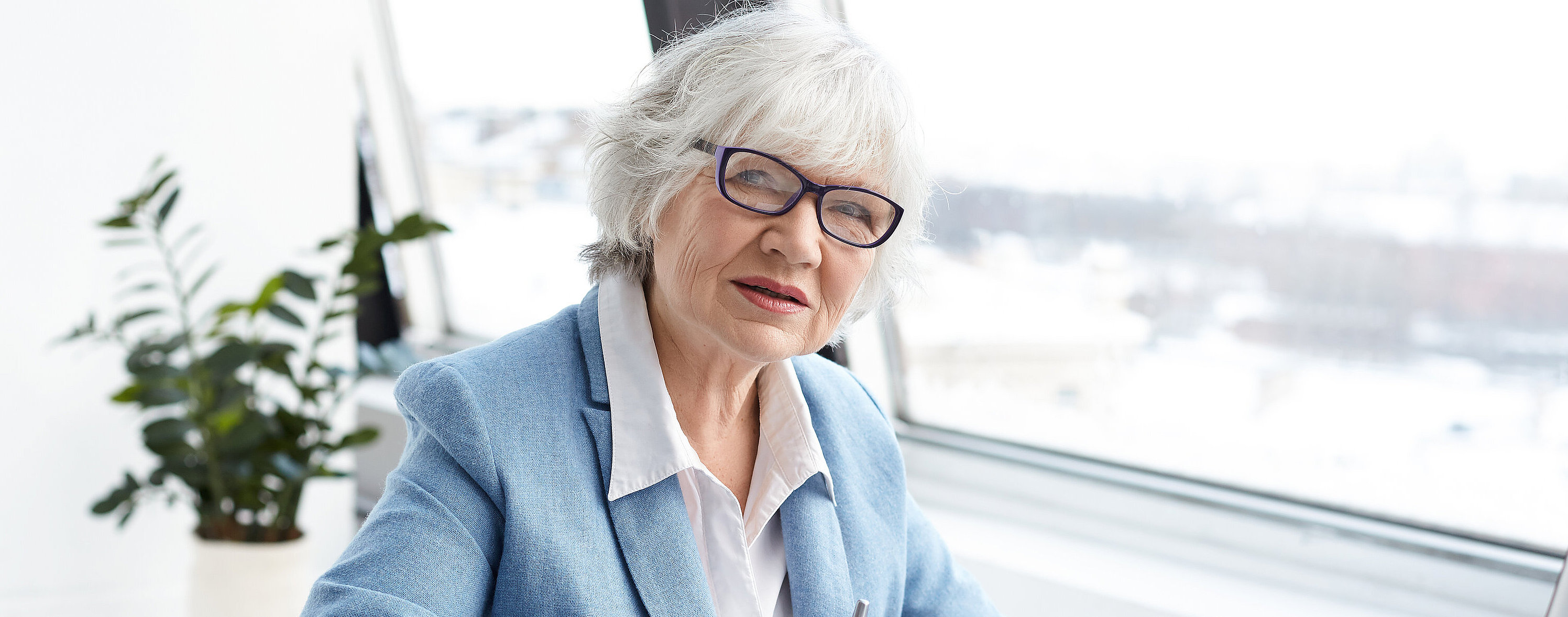 Attractive serious female chief executive officer of mature age sitting at her office with laptop, keyboarding and signing papers on desk, having confident look. People, aging, job and career concept