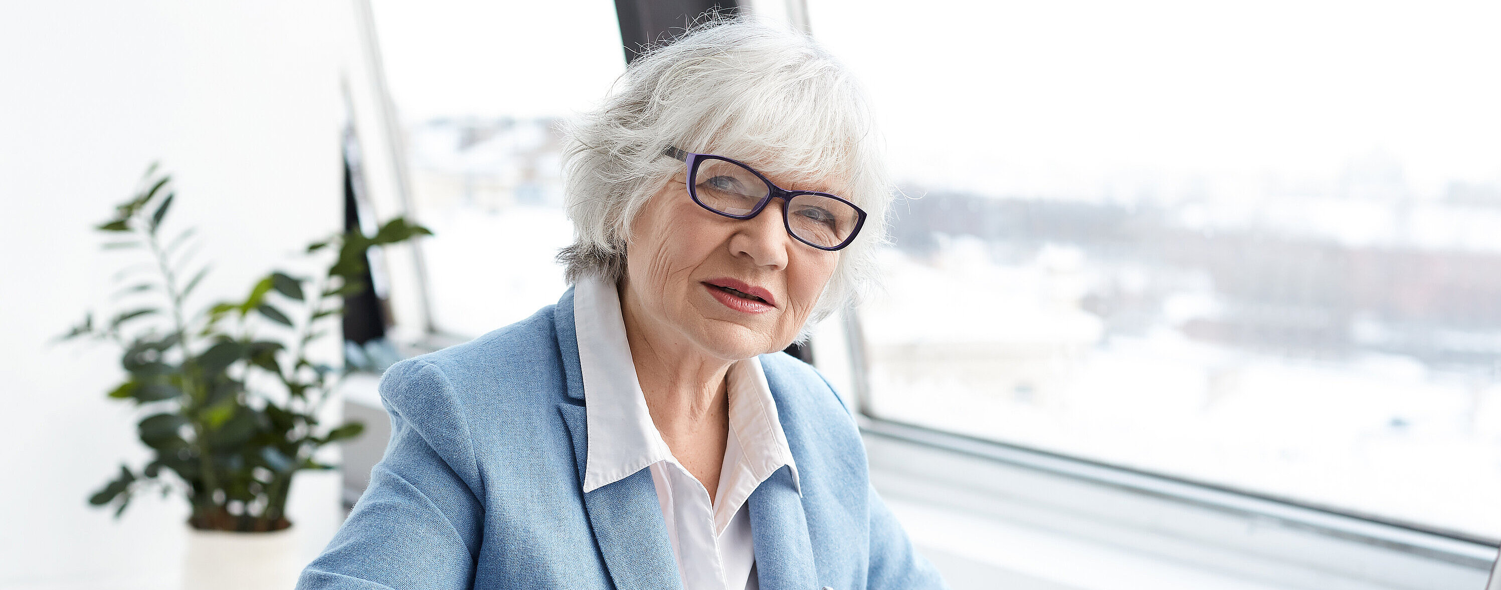 Attractive serious female chief executive officer of mature age sitting at her office with laptop, keyboarding and signing papers on desk, having confident look. People, aging, job and career concept