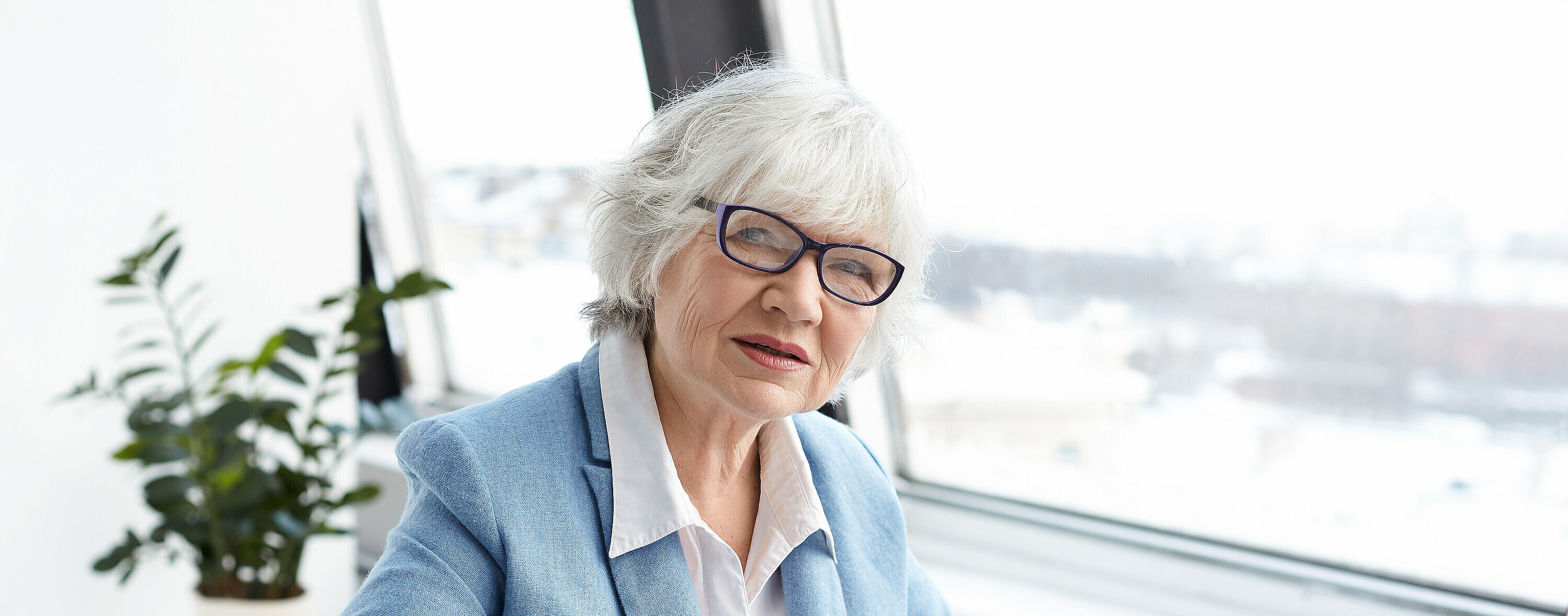 Attractive serious female chief executive officer of mature age sitting at her office with laptop, keyboarding and signing papers on desk, having confident look. People, aging, job and career concept