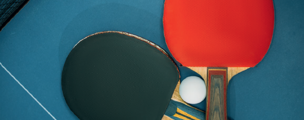 Tischtennisschläger auf einem Tischtennistisch liegend