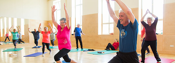 Das Foto zeigt ältere Menschen bei Gymnastikübungen im Turnsaal.