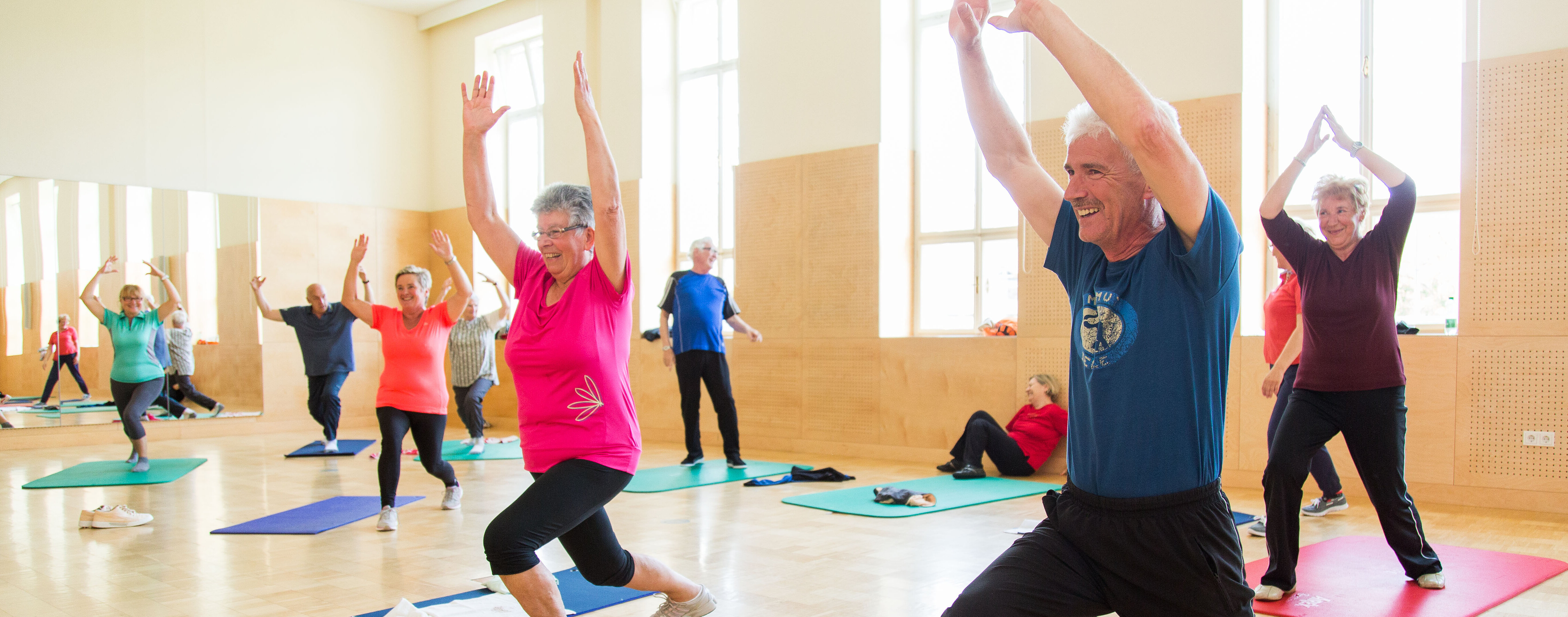 Das Foto zeigt ältere Menschen bei Gymnastikübungen im Turnsaal.