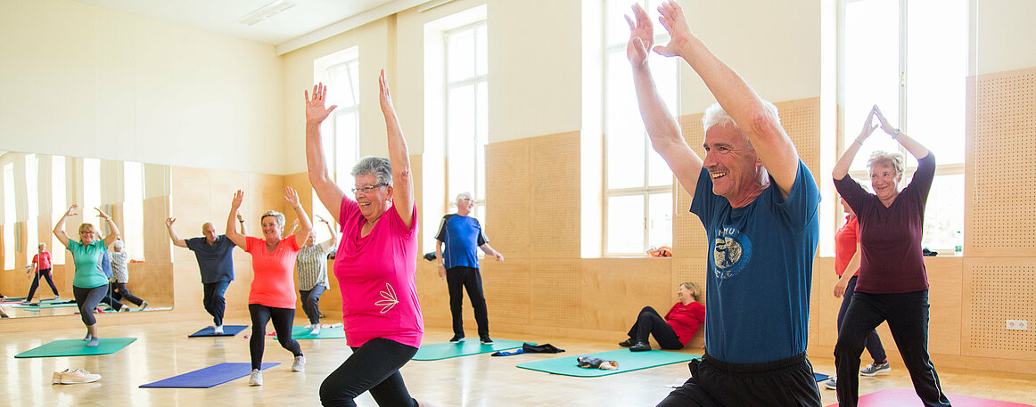 Das Foto zeigt ältere Menschen bei Gymnastikübungen im Turnsaal.