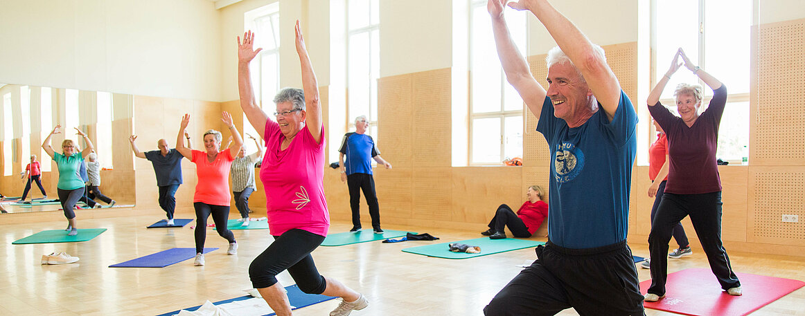 Das Foto zeigt ältere Menschen bei Gymnastikübungen im Turnsaal.