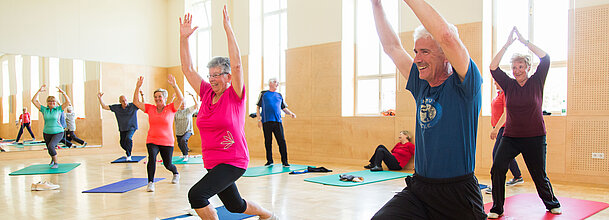 Das Foto zeigt ältere Menschen bei Gymnastikübungen im Turnsaal.