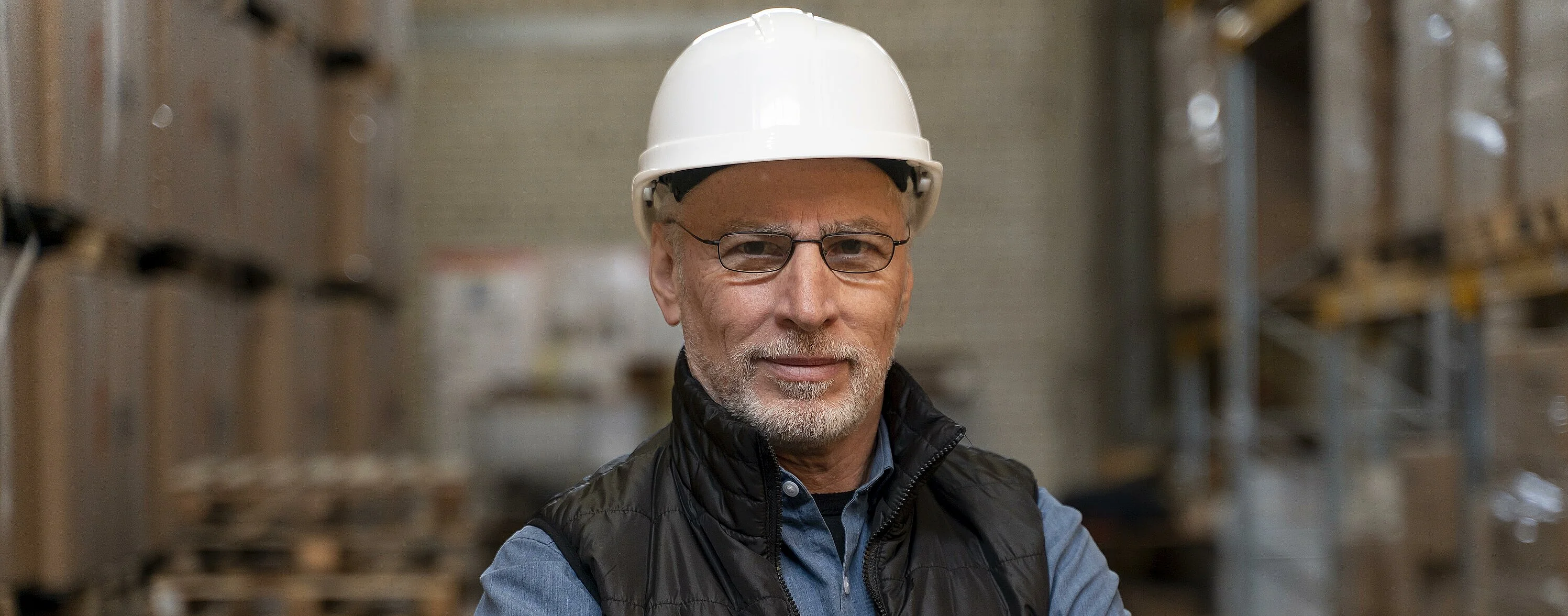 Mann mit Schutzhelm und Brille in einem Lager