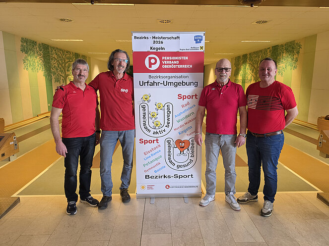 Zwei Männer links vom Rollup und zwei Männer stehen rechts davon.