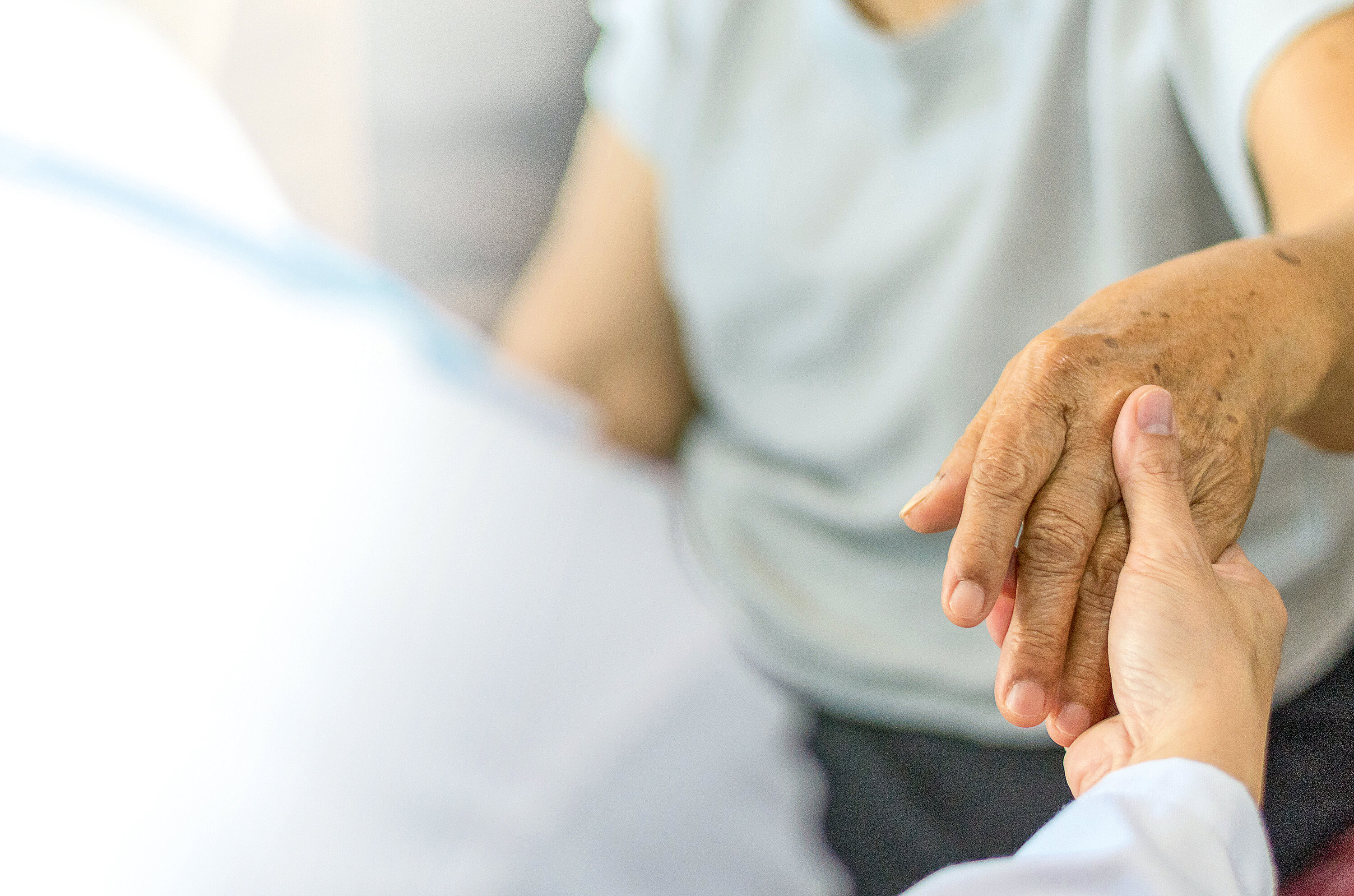 Parkinson and alzheimer female senior elderly patient hand with physician doctor exam in hospice care room.